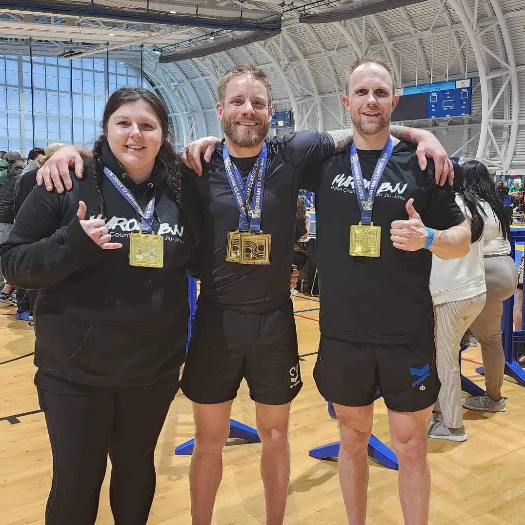 head coach shaun wearing two gold medals with two students also wearing gold medals at a competition